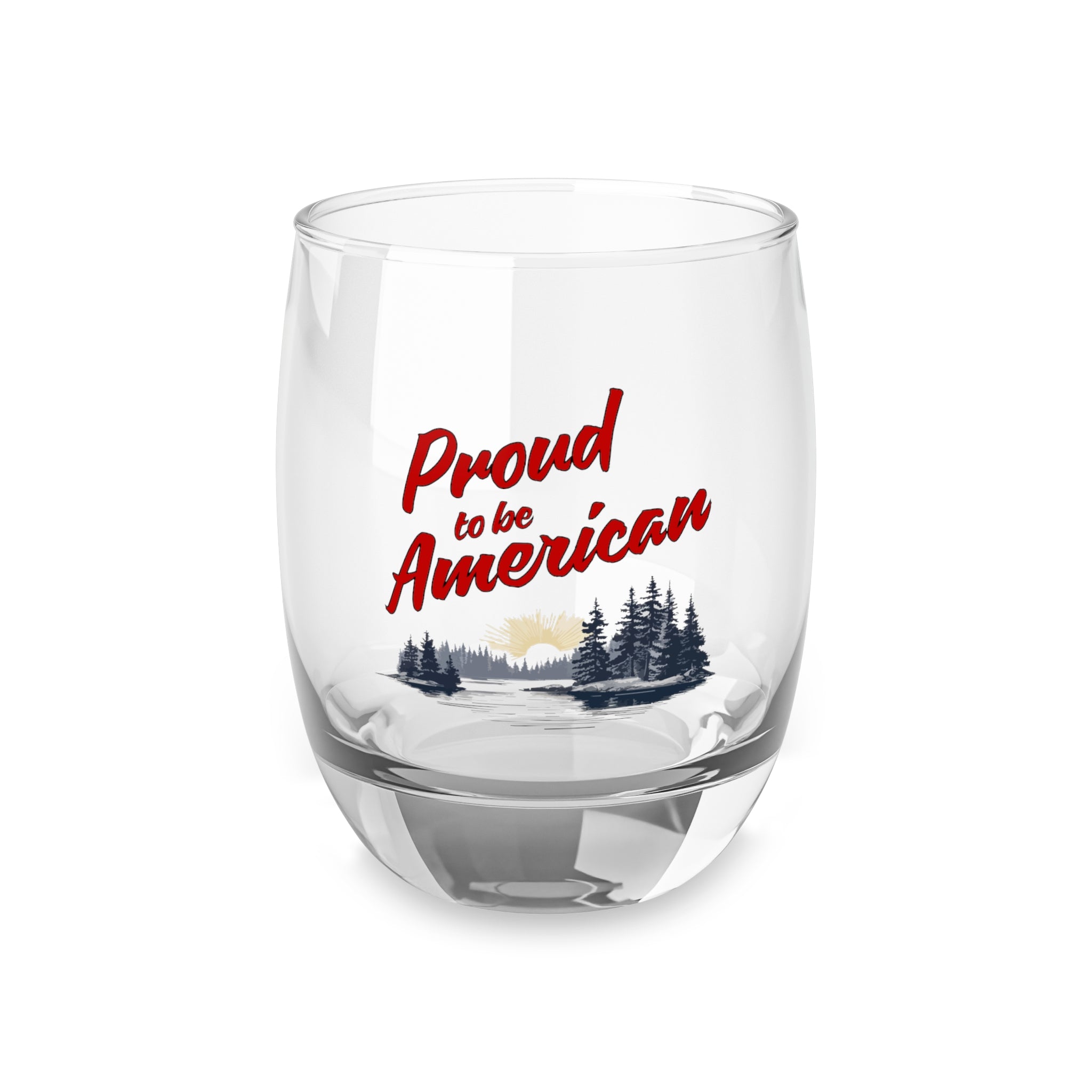 A clear whiskey glass with a 'Proud to be American' print on one side, featuring a patriotic design with a flag and trees in the background.